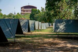 The simple and normal empty Canvas Tents in the row and column on the grass field at outdoor field in afternoon time.a photo