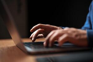 Hands typing on a laptop in a dimly lit room during the evening hours photo