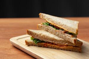 Deliciously stacked sandwich made with whole grain bread and fresh ingredients served on a wooden platter photo