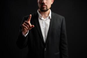 Businessman gestures with pointer finger in a serious demeanor against dark background during professional setting photo