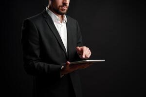 Business professional interacts with tablet in studio setting against dark background photo