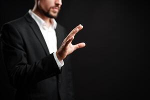 Professional man gesturing with hand against dark background in a corporate setting during afternoon hours photo