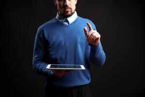 Professional man interacts with tablet in a dark studio setting during a digital presentation photo