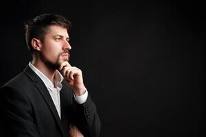 Man in a business suit contemplating ideas against a dark background in a studio setting photo