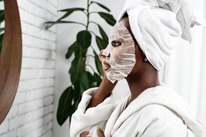 Woman applying a face mask while looking in the mirror at home spa setting during morning routine photo