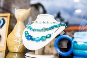 Turquoise and pearl necklaces on white display stand. Handmade jewelry, ocean-inspired design, and artisan accessories for summer style. photo