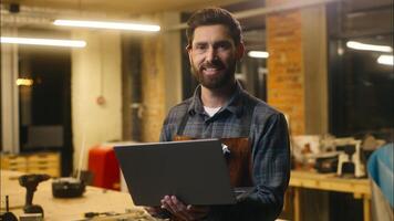 Positive Caucasian wood master man typing laptop online in workshop small business craftsman guy using computer device male joiner worker smile carpenter virtual shopping application Internet website photo