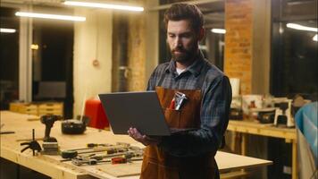 Caucasian wood master man typing laptop shopping app online in workshop builder handyman guy using Internet pc carpenter male buying goods artist architect browsing website small business cyberspace photo