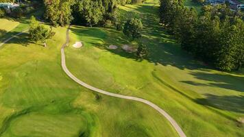 Drone footage captures a lush golf course with winding paths and sand bunkers under warm sunset lighting video