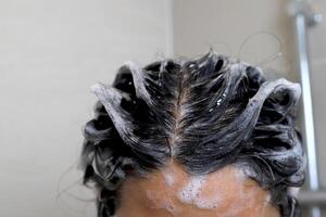 A woman is taking a shower and washing her hair in the bathroo photo