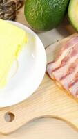 A close-up sequence of various healthy fats including avocado, bacon, butter, sunflower seeds, and almonds on a wooden board video