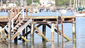 Wooden pier in Akaroa, New Zealand, with calm waters and distant boats. Bright daylight enhances the serene coastal atmosphere video