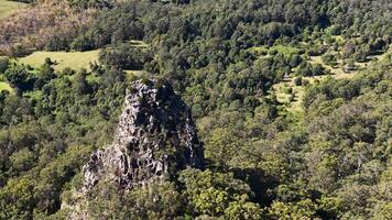 Aerial footage showcasing Nimbin Rocks surrounded by dense forest and greenery in bright daylight video