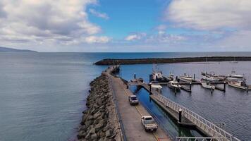 Drone captures Apollo Bay's serene harbor, showcasing boats, jetty, and rock wall under clear skies with calm waters video