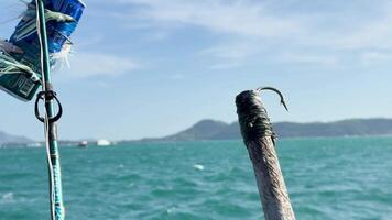 A fishing rod with a recycled can lure bobs in the ocean near Phuket, Thailand, under bright daylight video