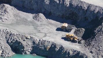 Drone footage captures excavators and trucks working in a sunlit quarry, highlighting industrial activity and rugged terrain video