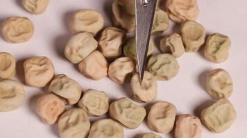 Close-up of a scalpel sorting dwarf pea seeds on a white surface under bright lighting video