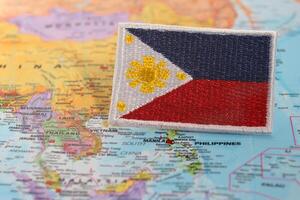 Horizontal eco friendly Philippines flag PH flag made from fabric and thread, placed over world map highlighting Manila under studio lighting. Symbolizing National Day, Earth Day photo