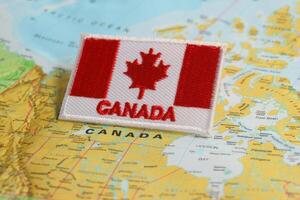 Horizontal eco friendly Canada flag CA flag embroidered with CANADA below, placed on world map highlighting Ottawa under studio lighting. Symbolizing National Day, Earth Day photo