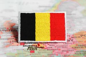 Horizontal shot of embroidered Belgium flag placed on Brussels on world map. Symbol of cultural travel, patriotism and national pride. photo