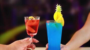 Two vibrant cocktails clink in a lively bar setting, highlighting colorful drinks and festive atmosphere with dynamic lighting video