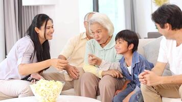 A joyful family shares popcorn and laughter in a cozy living room setting with bright, natural lighting video