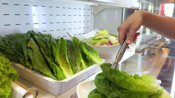 Hands selecting crisp lettuce leaves from a display for a Korean BBQ meal. Bright lighting enhances the fresh, green produce video