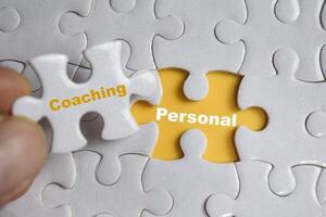 Hand holding piece of jigsaw puzzle with word Coaching or personal. Business and finance concept photo