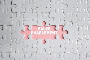 Hand holding piece of jigsaw puzzle with word Sales Enablement. Business and finance concept photo