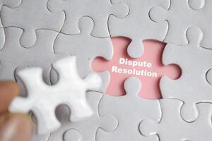 Hand holding piece of jigsaw puzzle with word Dispute Resolution. Business and finance concept photo