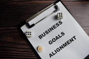 Concept of Business goals alignment write on clipboard isolated on Wooden Table. photo