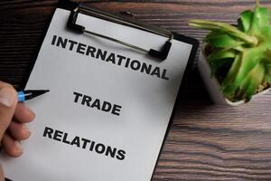 Concept of International trade relations write on clipboard isolated on Wooden Table. photo