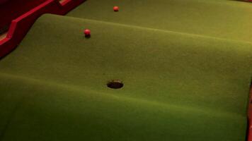 A red golf ball moves back and forth on a miniature golf course at night, illuminated by soft lighting video