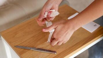 A person bandages a bleeding finger in a well-lit kitchen setting, using a plaster strip video