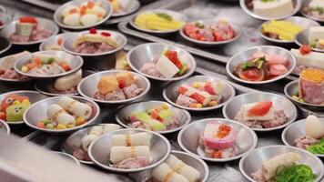 A vibrant display of dim sum dishes being arranged in a bustling market setting, showcasing diverse culinary delights video