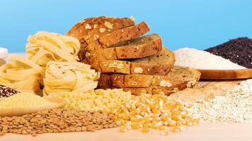 Various grains, pasta, and bread arranged on a wooden surface with a bright blue backdrop, highlighting texture and color video