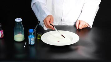 A scientist demonstrates a vibrant color reaction in milk using household items, showcasing a simple yet captivating experiment video