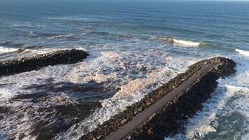 Aerial view of ocean waves hitting a stone breakwater at Brunswick Heads, NSW. Captured in natural daylight with dynamic movement video