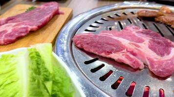Sizzling meat on a grill with fresh lettuce in a vibrant Bangkok setting. Bright lighting enhances the lively dining atmosphere video