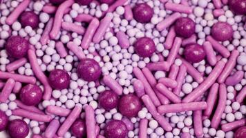 Close-up of pink and purple sprinkles rotating, highlighting texture and color in a macro perspective video