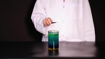 A scientist in a lab coat conducts a dry ice experiment, showcasing chemical reactions in a beaker with vibrant colors video