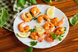 Cooking fried shrimps with aromatic spices and lemon in a plate on a wooden photo