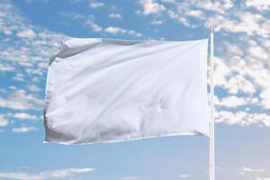 White flag stretches with movement in open sky, ideal for peaceful concepts, surrender symbolism, or minimalist branding presentations photo