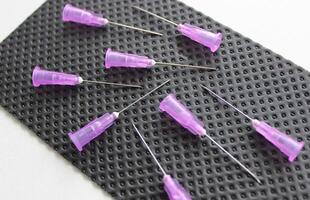 Open needles for disposable syringes are scattered on a black medical napkin photo