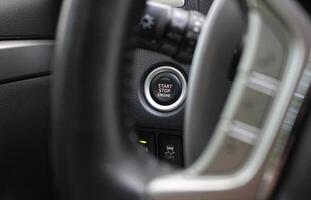 View of the electronic engine start button through the blurred steering wheel spokes photo
