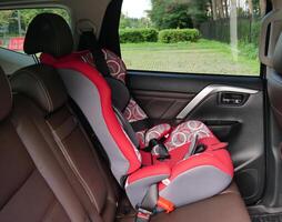 Red infant car seat in the back seat secured with standard seat belts photo