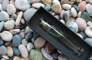 A bottle of perfume in a black velvet box on a decorative stones photo
