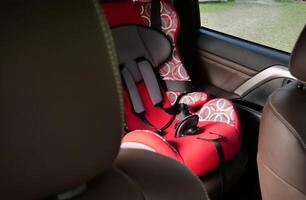 Child safety seat in the rear seat of a car fixed with seat belts photo