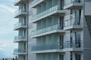 Facade of white modern street building with many glass balconies. Urban architecture. photo