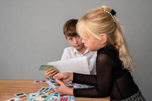 Children, Cards, Learning - Two kids play a card game at a table, learning and having fun. photo